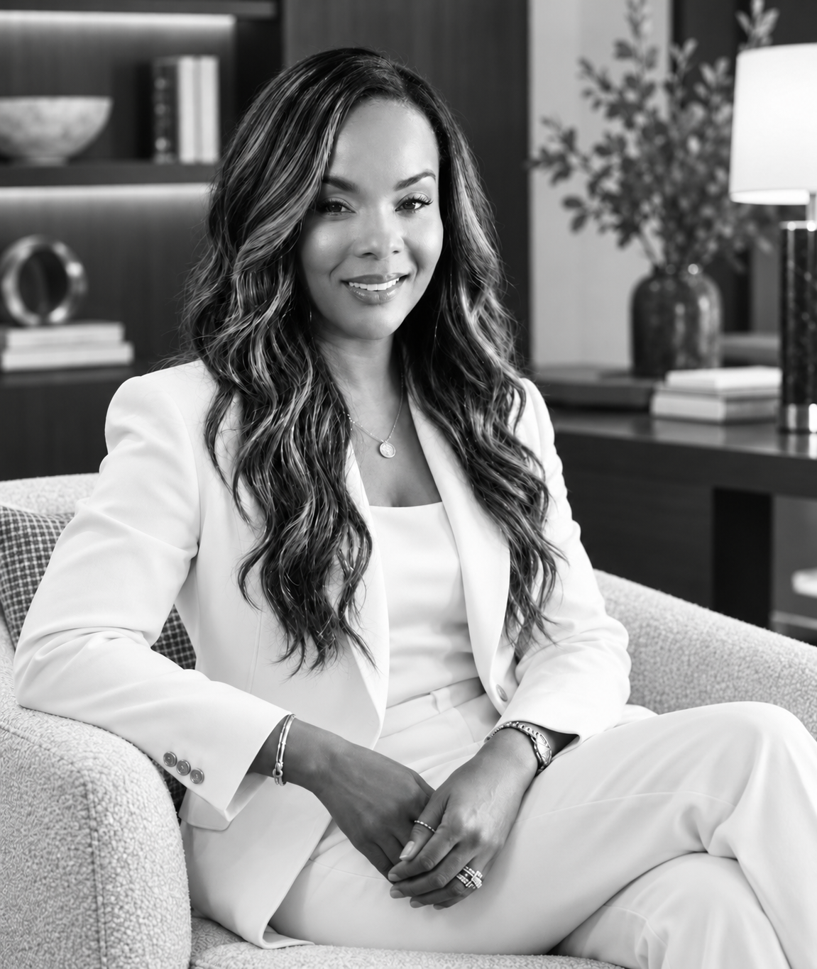 Dr. Renée Baker seated in an ivory suit, in black and white.